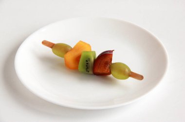 Taze meyvelerden yapılmış çocuk partisi için meyve kebabı. Taze kivi, erik, üzüm, ahşap çubuklarda hurma. Doğum günü partisi için egzotik meyve mezeleri..