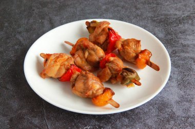 Tabaktaki tahta çubuklarda tavuk budu kebabı. Sıcak meze - kırmızı biberli tavuk şişi ve soğan ve taze sebze salatası.. 