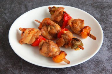 Tabaktaki tahta çubuklarda tavuk budu kebabı. Sıcak meze - kırmızı biberli tavuk şişi ve soğan ve taze sebze salatası.. 