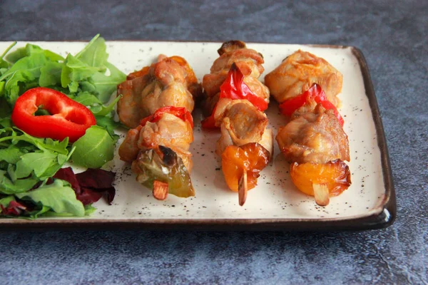 Tabaktaki tahta çubuklarda tavuk budu kebabı. Sıcak meze - kırmızı biberli tavuk şişi ve soğan ve taze sebze salatası.. 