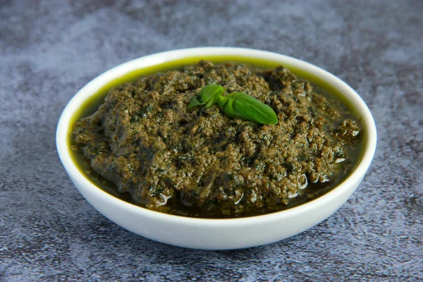 Beyaz tabakta vejetaryen sosu. Vejetaryenler ve vejetaryenler için peynirsiz yeşil fesleğen soslu pesto.. 