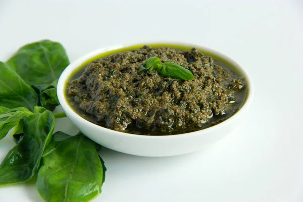 Beyaz tabakta vejetaryen sosu. Vejetaryenler ve vejetaryenler için peynirsiz yeşil fesleğen soslu pesto.. 