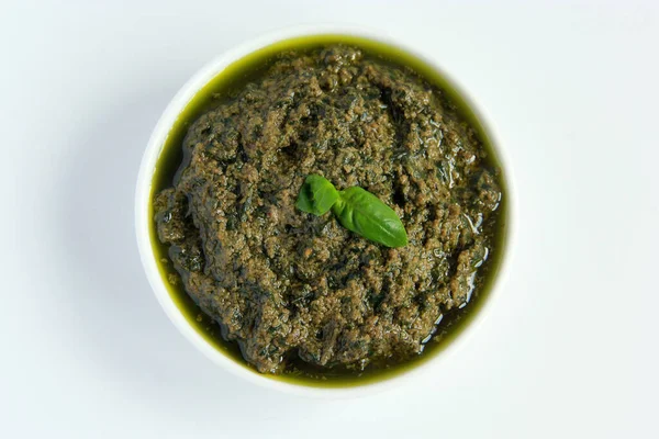 Beyaz tabakta vejetaryen sosu. Vejetaryenler ve vejetaryenler için peynirsiz yeşil fesleğen soslu pesto.. 