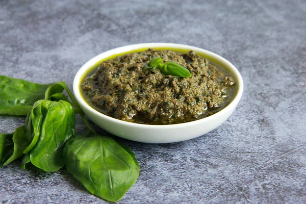 Beyaz tabakta vejetaryen sosu. Vejetaryenler ve vejetaryenler için peynirsiz yeşil fesleğen soslu pesto.. 