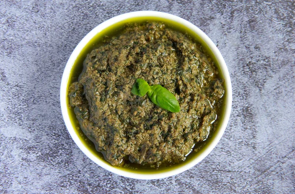 Beyaz tabakta vejetaryen sosu. Vejetaryenler ve vejetaryenler için peynirsiz yeşil fesleğen soslu pesto.. 