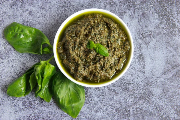 Beyaz tabakta vejetaryen sosu. Vejetaryenler ve vejetaryenler için peynirsiz yeşil fesleğen soslu pesto.. 
