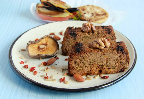 Nut roast - delicious vegan meatloaf made of nuts, vegetables and mushrooms. Healthy vegetarian food - vegan nutroast on the plate.