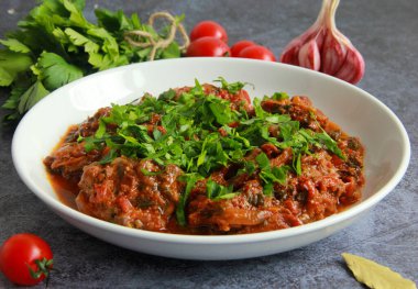 Geleneksel tavuk chakhokhbili tabakta. Gürcistan usulü haşlanmış tavuk, domates sosu ve taze otlar..