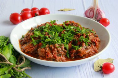 Geleneksel tavuk chakhokhbili tabakta. Gürcistan usulü haşlanmış tavuk, domates sosu ve taze otlar..