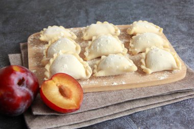 Traditional ukrainian varenyky with fresh plum filling. Delicious dumpling with fruit filling. Raw handmade vareniki with plums.