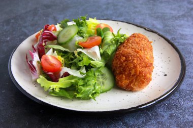 Beyaz tabakta sebze salatalı tavuk pirzolası. Ev yapımı tavuk Kyiv - Lezzetli aile yemeği.