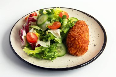 Beyaz tabakta sebze salatalı tavuk pirzolası. Ev yapımı tavuk Kyiv - Lezzetli aile yemeği.