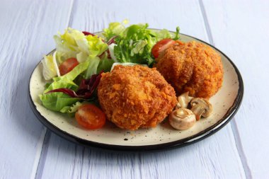 Mantarlı ve peynirli tavuk pirzolası. Mantarlı tavuk pirzolası ve tabakta sebze salatası..