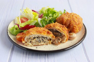 Mantarlı ve peynirli tavuk pirzolası. Mantarlı tavuk pirzolası ve tabakta sebze salatası..