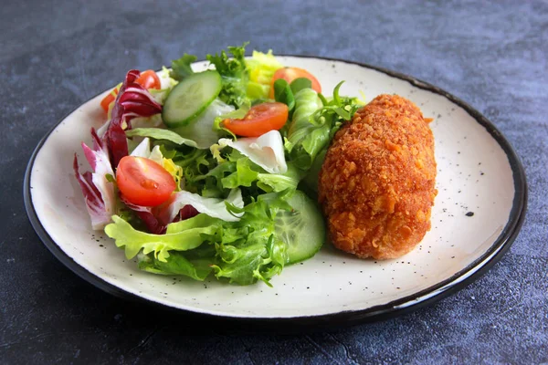 Beyaz tabakta sebze salatalı tavuk pirzolası. Ev yapımı tavuk Kyiv - Lezzetli aile yemeği.