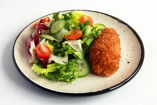 Beyaz tabakta sebze salatalı tavuk pirzolası. Ev yapımı tavuk Kyiv - Lezzetli aile yemeği.