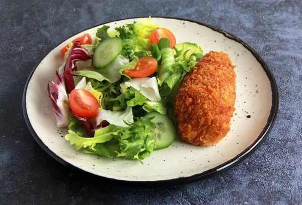 Beyaz tabakta sebze salatalı tavuk pirzolası. Ev yapımı tavuk Kyiv - Lezzetli aile yemeği.