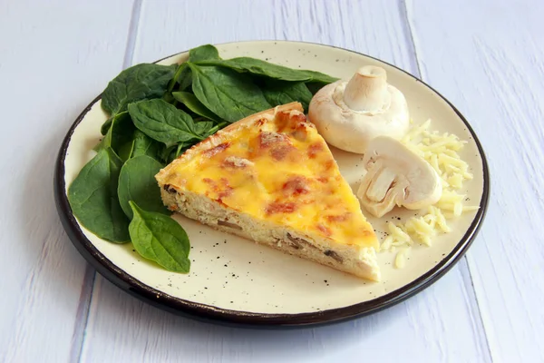 Homemade quiche with chicken, mushrooms, spinach and cheese. Delicious pie with savoury filling for breakfast or dinner.