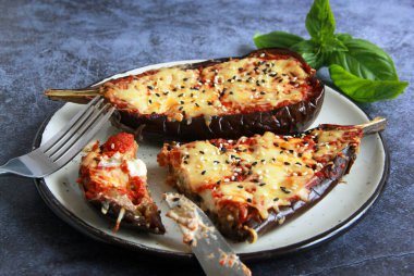 Domates ve peynirli patlıcan dolması. Fırında pişmiş patlıcan tabakta yarımlar.