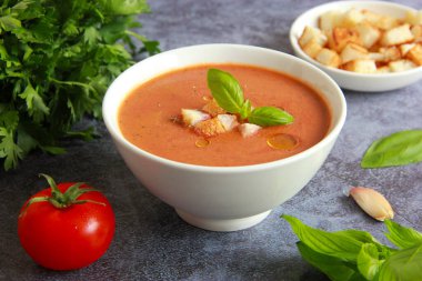 Beyaz kasede ev yapımı gazpacho çorbası. Soğuk İspanyol domates çorbası, kızarmış ekmek, sarımsak ve fesleğen..