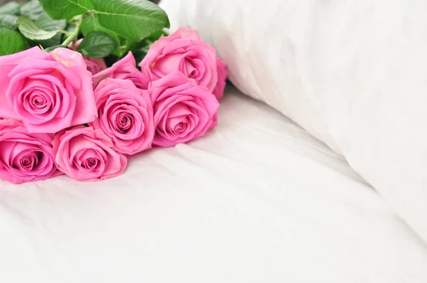 Buquê de rosas cor-de-rosa na roupa de cama branca — Fotografia de Stock