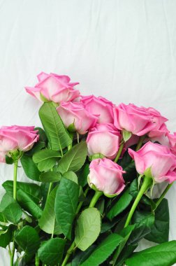 Yataktaki beyaz çarşafların üzerinde pembe güller 