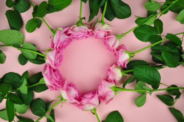 Masanın üzerinde daire şeklinde pembe güllerin bileşimi 