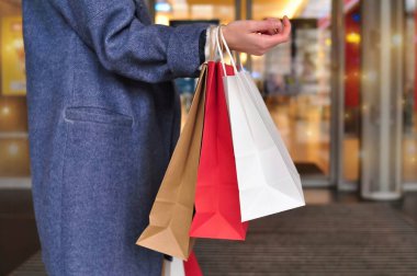 Alışveriş merkezinde kırmızı beyaz alışveriş torbaları tutan müşterinin eli, kopyalama alanı