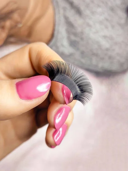 Stripe with black fake lashes in hand with pink manicure . High quality photo