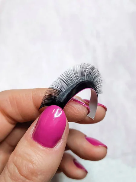 Stripe with black fake lashes in hand with pink manicure . High quality photo