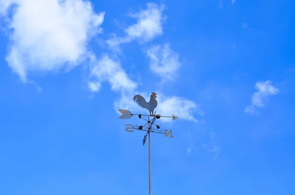 Rooster weather vane in blue cloudy sky copy space . High quality photo