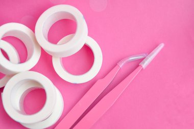 Kirpik için beyaz musluk ve cımbız. Kirpikçiler için pembe arka planda. Boşluğu kopyala