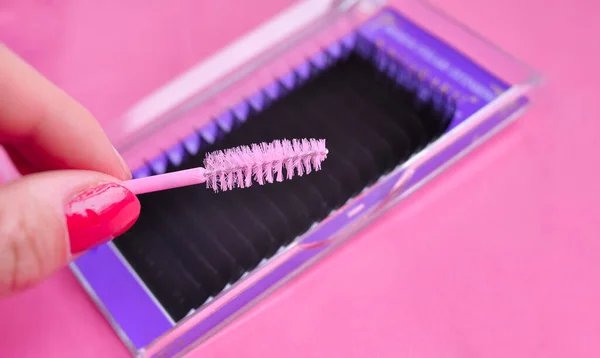 Pink brush and pallet of fake lashes for lash extensions in beauty salon copy space