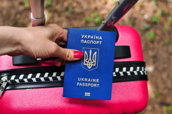 Biometric Ukrainian passport of refugee on pink Travel bag — стокове фото