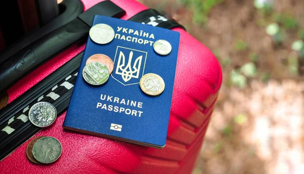 Ukrainian international passport pences and pink travel bag of refugee — стокове фото
