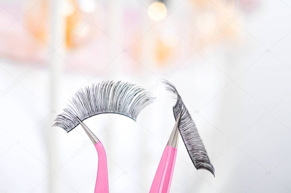 Dramatic strip lashes in pink tweezers for gluing on own,womans make up .