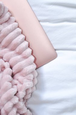 Yatak odasındaki beyaz çarşaflara pembe dizüstü bilgisayarı kapat, serbest çalışma konsepti