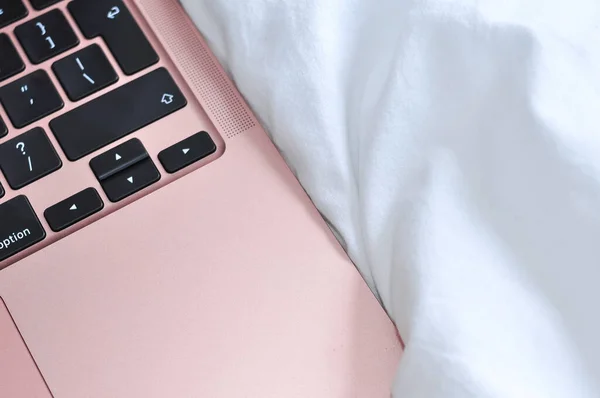 close up of pink laptop on white linen in bedroom,freelance work concept