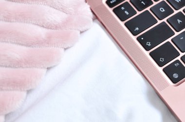 Yatak odasındaki beyaz çarşaflara pembe dizüstü bilgisayarı kapat, serbest çalışma konsepti