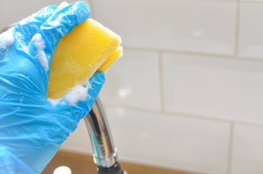 Ellerinizi mavi eldivenlerle kapayın. Çamur temizlemek, temizlik konsepti, ev işleri için sarı bez kullanın.