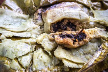 Meksika, Oaxaca 'da Tamale yemek. Tamal masası, muz yaprağına sarılmış tavuk ve köstebek zencisi dolu..