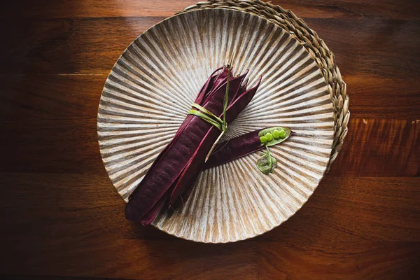 Açık tohumlu bir fasulye kabuğunun yanında tabakta duran bir demet mor Guaje fasulyesi. Oaxaca, Meksika.