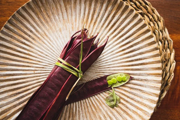 Açık tohumlu bir fasulye kabuğunun yanında tabakta duran bir demet mor Guaje fasulyesi. Oaxaca, Meksika.