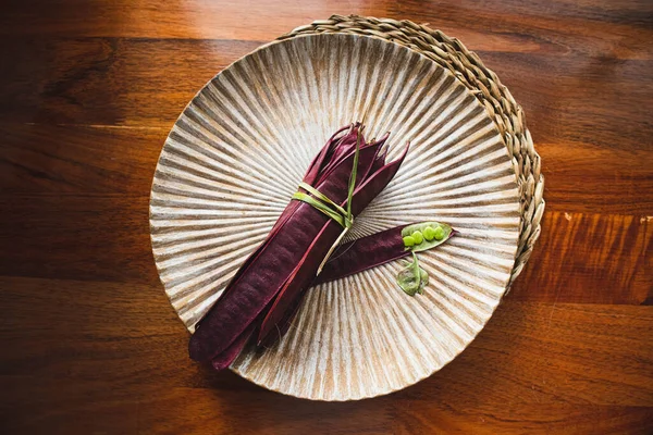 Açık tohumlu bir fasulye kabuğunun yanında tabakta duran bir demet mor Guaje fasulyesi. Oaxaca, Meksika.