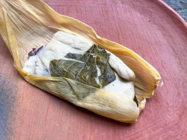 Bir Oaxacan tamale ile hoja noel baba masa dışında sarılmış ve tuğla arkaplan ile fasulye ile dolu