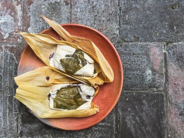Masanın dışına sarılı iki Oaxacan tamale ve tuğla kaplı fasulye.