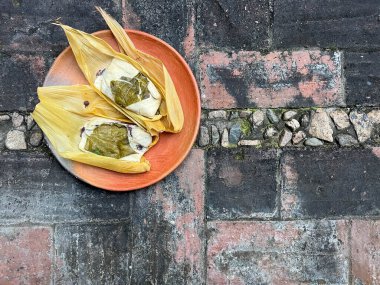 Masanın dışına sarılı iki Oaxacan tamale ve tuğla kaplı fasulye.