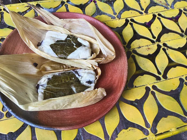 正座の外側にはほうじ茶のサンタが包まれ 黄色の背景をした豆で満たされたOaxacan Tamales — ストック写真