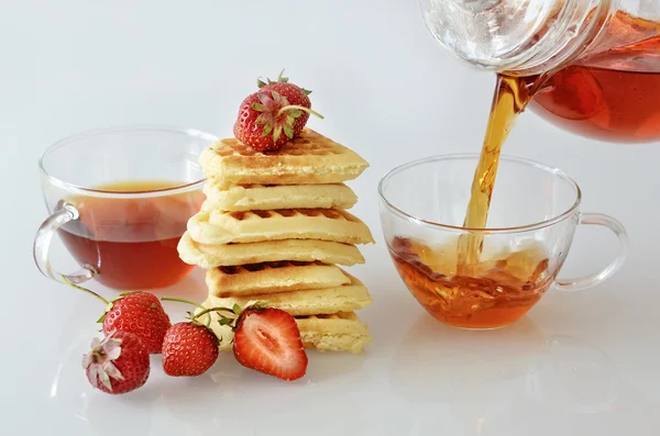 Chá derramando em uma xícara com waffels e morangos — Fotografia de Stock