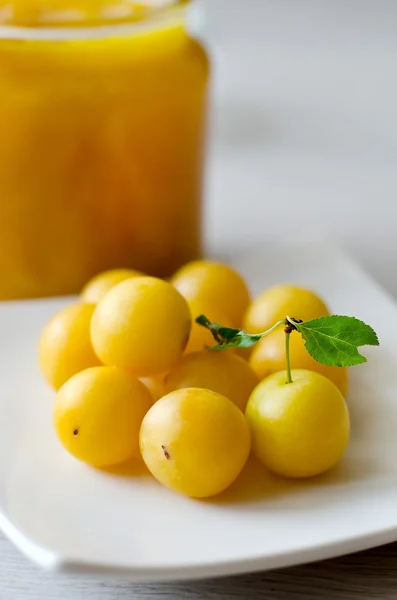 Prunes jaunes sur l'assiette et une boîte de confiture — Photo